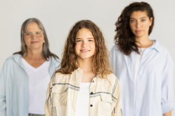 Confident smiling adult, elderly women and teen girl isolated on gray studio background