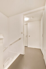 an empty room with white walls and grey flooring on the right, there is a door leading to another room