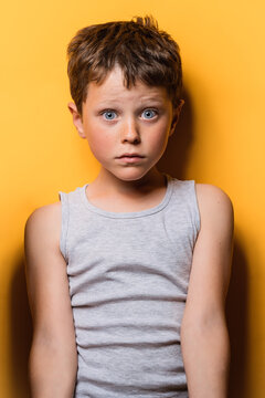 Shocked kid looking at camera with astonishment in yellow studio