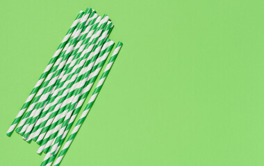 Paper cocktail straws on a green background, top view