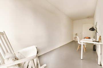 an empty room with a desk and chair on the left side, there is a white wall in the background