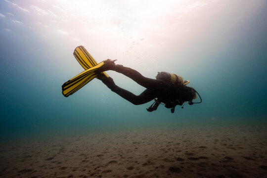 Anonymous person in diving mask fins swimming underwater