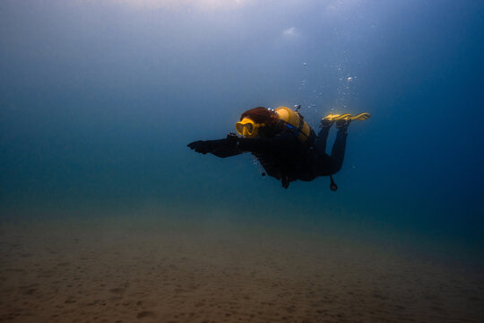 Anonymous person in diving mask fins swimming underwater