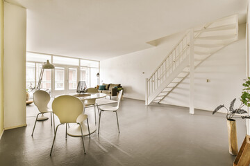 a living room with some chairs and a staircase leading up to the second floor in an apartment that has been painted white