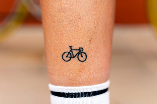 Unrecognizable person with small bicycle tattoo on leg standing in daylight