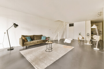 a living room with a couch, chair and ladder in the middle of the room there is a white rug on the floor