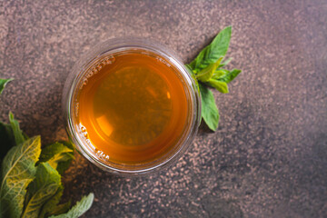 Close up of fresh mint tea in a cup and leaves on the table top view