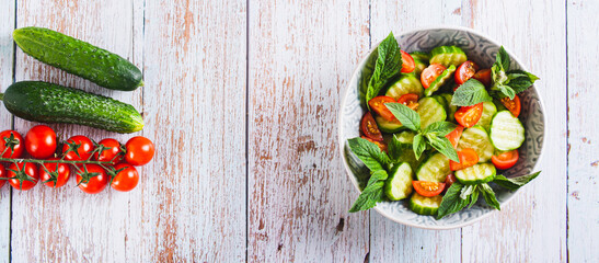Diet salad of cucumbers, tomatoes and mint in a bowl on the table top view web banner