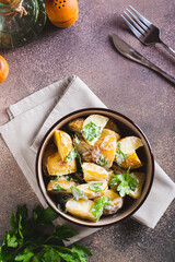 Delicious potato salad with parsley and mayonnaise in a plate on the table top and vertical view