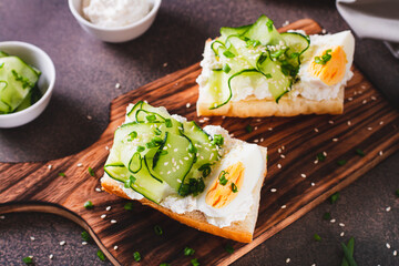 Bruschetta with ricotta, cucumber, boiled egg and sesame seeds on a board