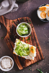 Bruschetta with ricotta, cucumber, boiled egg and sesame seeds on a board top and vertical view