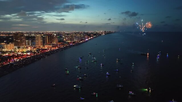 4th of July fireworks above coastline at sunset. City lights by the beach, Florida. Aerial view