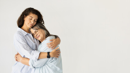 Positive adult woman hugging elderly lady, enjoy love, lifestyle, isolated on white studio...
