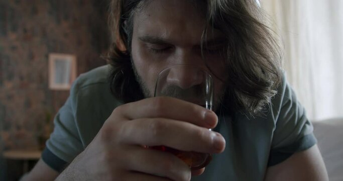 Man drinking alcohol daytime. Alcohol addiction problem. Abuse alcohol drinking. Glass of whiskey. Close up face of disturbed, troubled  man. Feeling angry, resentful, humiliated. Depressive thoughts