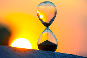 Hourglass on the background of a sunset. The value of time in life. An eternity.