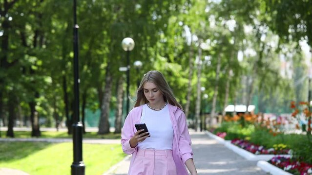 Young beautiful blonde girl with a mobile phone in a summer park