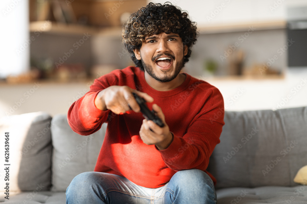 Sticker Online Competition Concept. Portrait of excited young indian man playing video games