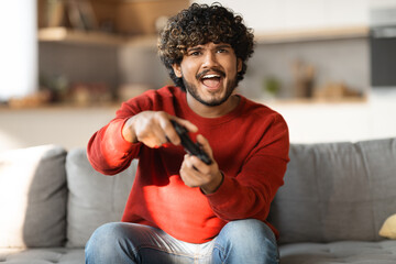 Online Competition Concept. Portrait of excited young indian man playing video games © Prostock-studio