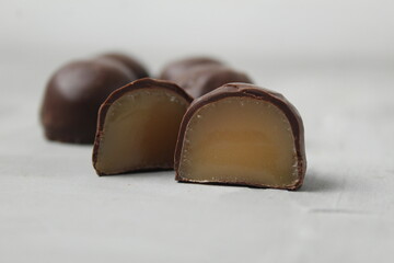 Chocolate body candy in a cut with a creamy praline filling on a white light background. Sweets...