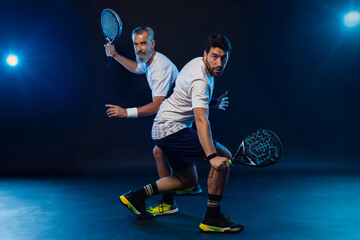 Padel tennis doubles. Two athletes players with racket. Man athlete with paddle racket on court with neon colors. Sport concept. Download a high quality photo for the design of a sports app - 621641611