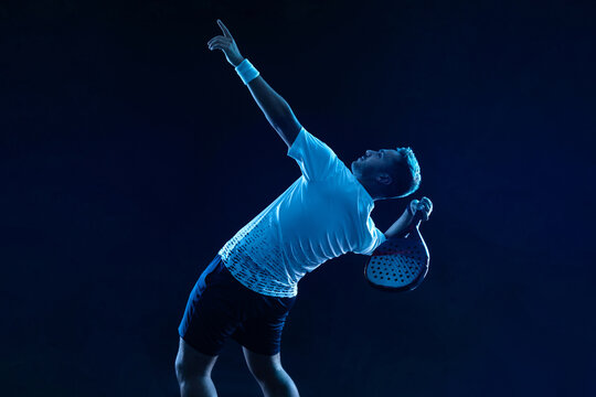 Padel tennis player. Padel open tour. Man athlete with paddle tenis racket on blue background. Sport concept. Download a high quality photo for sports website. © Mike Orlov