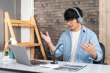 Male tutor wearing headset, using laptop and though camera to te