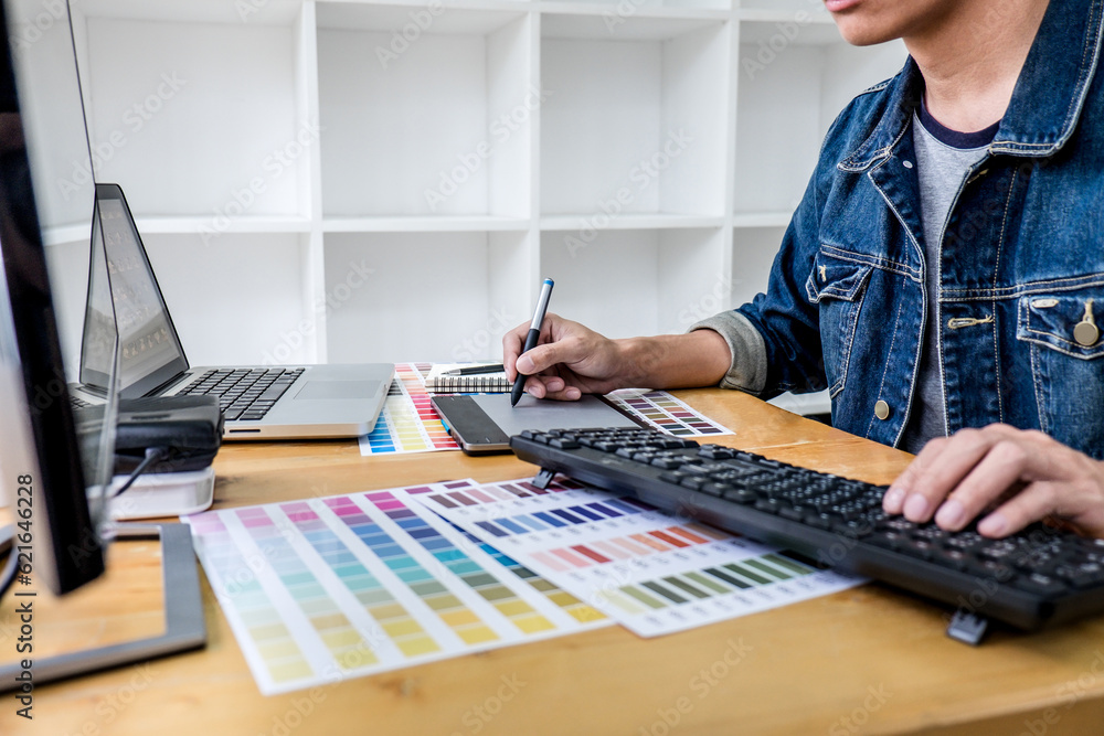 Poster Image of male creative graphic designer working on color selection and drawing on graphics tablet at workplace with work tools and accessories in workspace