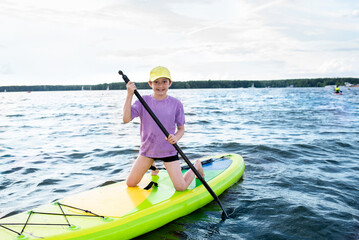 A 10-year-old boy rides a SUP board on a river or lake alone