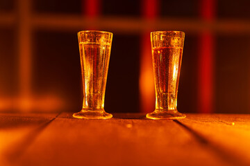 Two old vintage shot glasses with slivovitz on the old wooden table illuminated by orange candle...