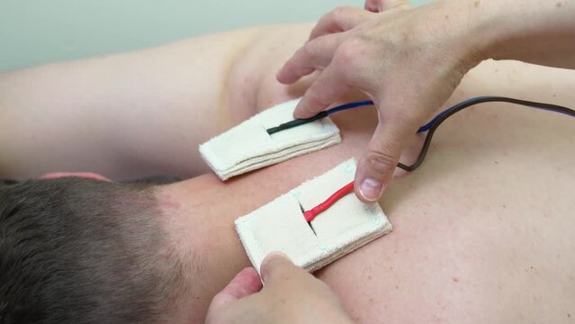 patient with an electrotherapy, electrical stimulation and electrophoresis device.