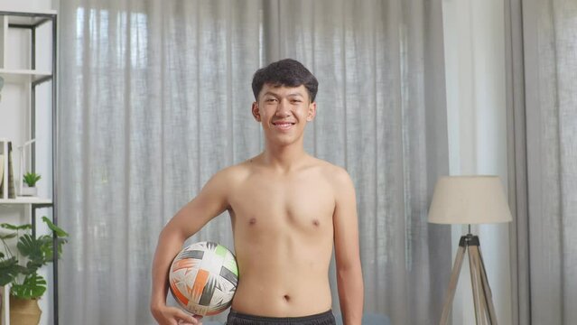 Asian Teenager Boy With Football Smiling To Camera After The Shirtless Workout At Home
