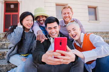 Group of multiracial best firends faving fun using a smartphone. Young people smiling and watching...