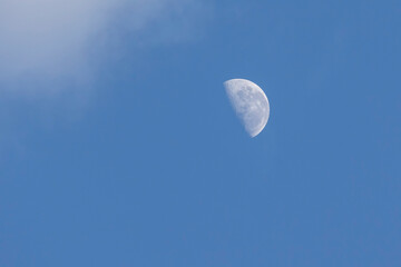 Moon waning phase on the blue sky between clouds. Nature is stunning. Astronomy.