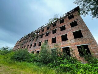 Unfinished bricks building. Abandoned house, not completed construction destroyed by time and covered with plants.