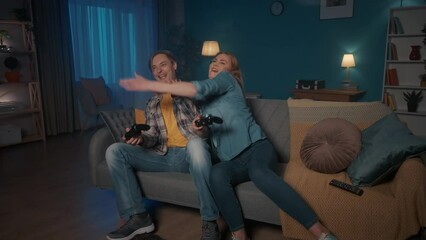 A married couple is playing a consular game. The woman closes man's eyes, but the man still wins. The woman is upset, but she plays again, and this time she wins. Man shows rock gesture.