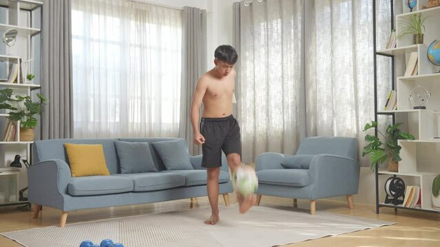 Full Body Of Asian Teenager Boy Doing Football Skills During The Shirtless Workout At Home

