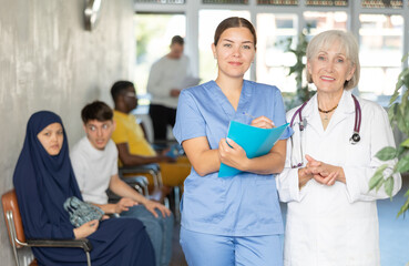 Obraz premium Elderly woman and young woman medics in uniform make notes in notebook at reception