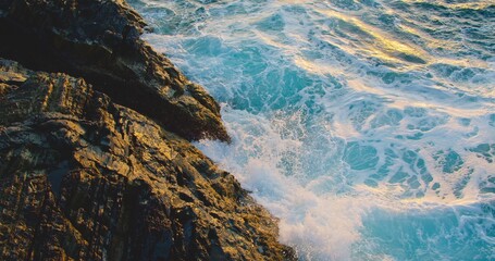 The untouched beauty of nature. The ability of the ocean to self-heal and self-purification of the waters of the world. Unpolluted environment. Splashing water on rocks at sunset in slow motion.