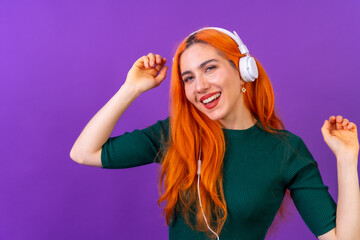 Redhead woman in studio photography smiling dancing on a purple background