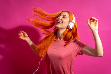 Naklejka premium Redhead woman in studio photography dancing on a pink background, in hard light