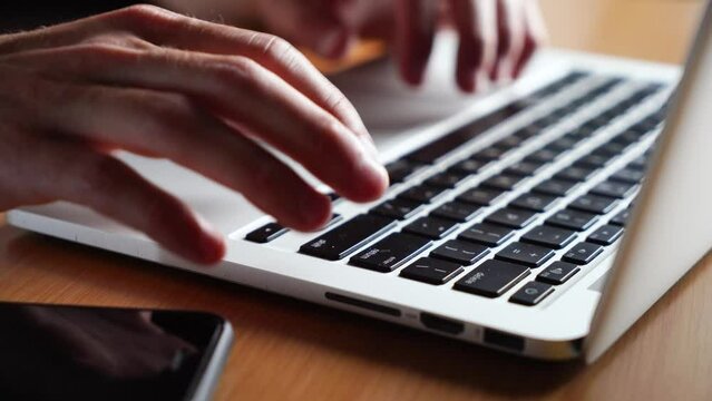 young man works typing on a laptop keyboard. Close-up