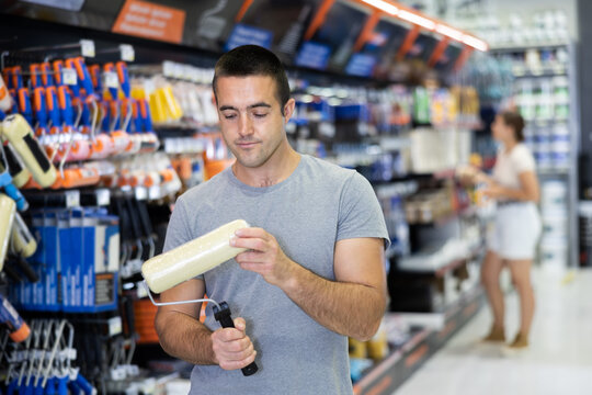 Confident man buying tools for house decoration in paint supplies store - paint roller
