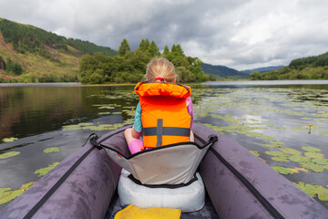 A young girl kayaking on a loch on a summers day in the Scottish Highlands 