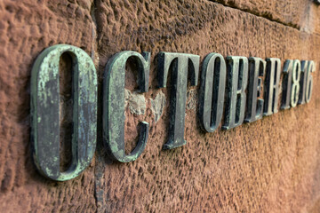 Steel letters on the stone. Word - October. Aged steel letters on a concrete wall. The inscription on the wall - October 1816.