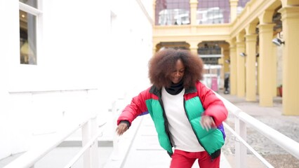 black woman dances with headphones freestyle outdoors with exterior building background
