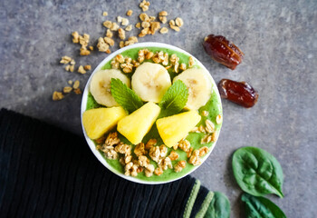 Matcha green tea breakfast superfoods smoothies bowl with chia, flax and pineapple, bananas, dates, spinach granola, kiwi. Overhead, top view, flat