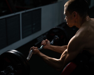 Man doing EZ barbell bicep exercises on Scott bench. 