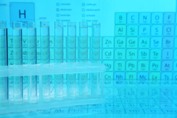Fototapeta premium Test tubes against periodic table of elements, toned in light blue. Space for text