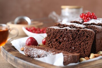 Tasty chocolate sponge cake with nuts and berries on table, closeup