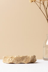 Background for parfume and cosmetic products of natural beige color. Stone podium and dry flower. Front view.